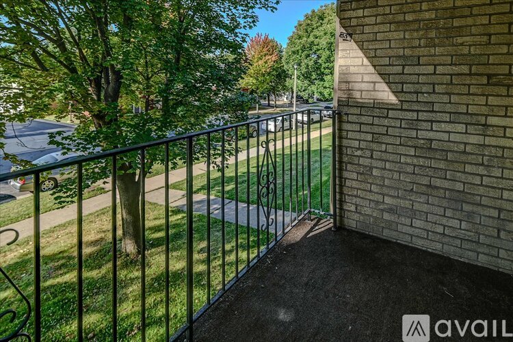 A balcony with a metal railing overlooks a grassy area.
