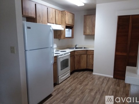A kitchen with a white refrigerator and wooden cabinets.