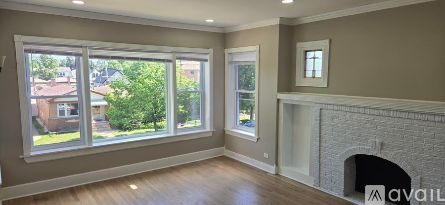 A living room with a fireplace and a large window overlooking a residential area.