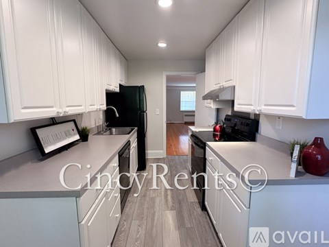 A kitchen with white cabinets and a black fridge.