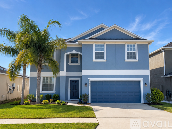 A two-story house with a blue garage door and a palm tree in front.