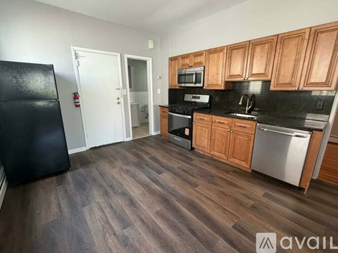 A kitchen with wooden cabinets and a black fridge.