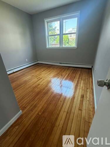 A room with wooden flooring and a window.