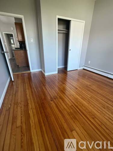 A room with wooden floors and two doors, one of which is open.