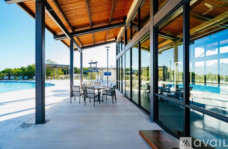 A covered outdoor seating area with tables and chairs overlooking a pool.