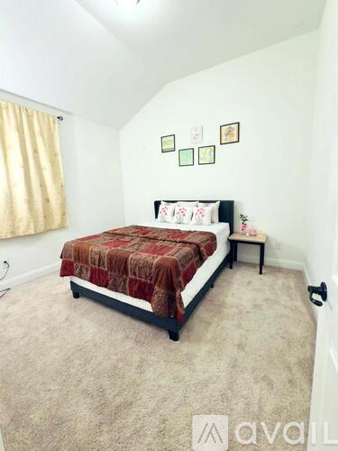 A bedroom with a bed, nightstand, and pictures on the wall.