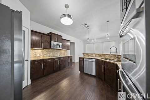 A modern kitchen with dark wood cabinets and stainless steel appliances.