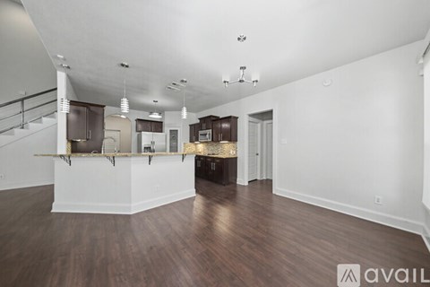 A spacious living room with hardwood floors and a staircase on the left side.