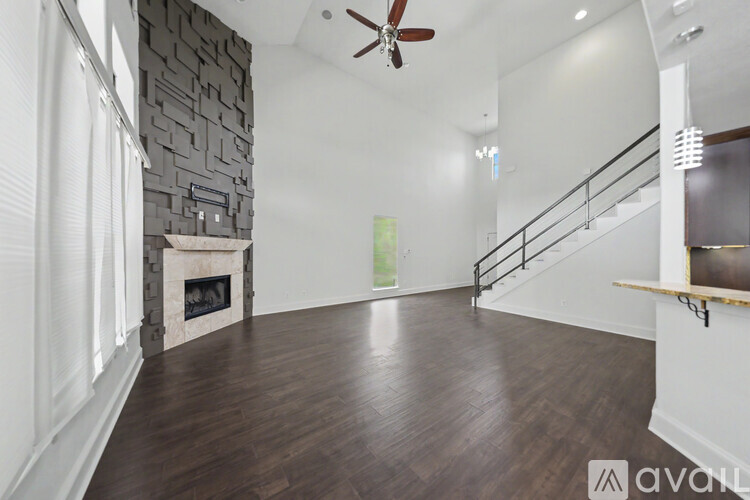 A spacious room with a fireplace and wooden flooring.