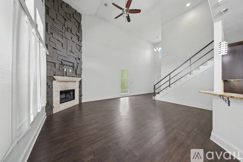 A spacious room with a fireplace and wooden flooring.