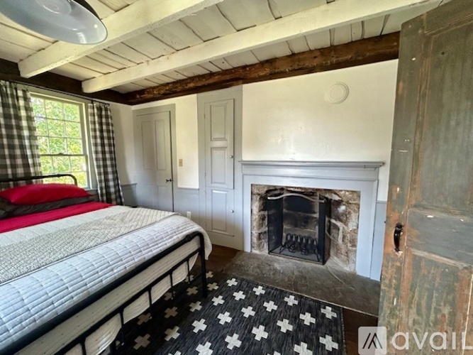 A bedroom with a bed, a fireplace, and a window with curtains.