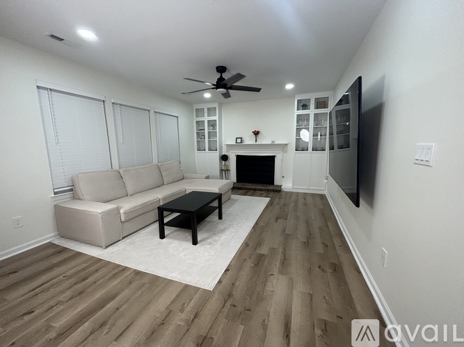 A living room with a beige couch, a black coffee table, and a flat screen TV mounted on the wall.