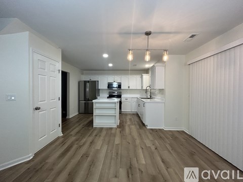 A kitchen with white cabinets and a wooden floor.