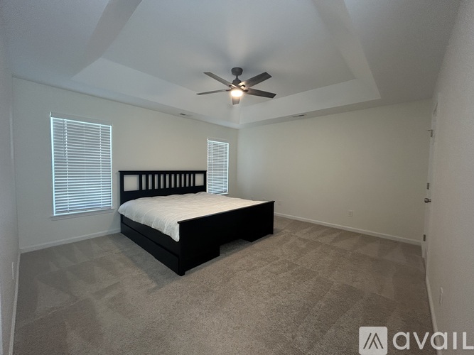 A bedroom with a bed, carpet, and a ceiling fan.