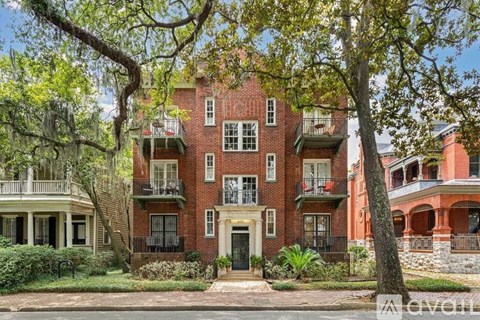 A red brick building with a balcony and a door in front.