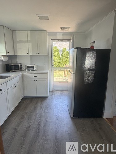 A kitchen with a black fridge and white cabinets.