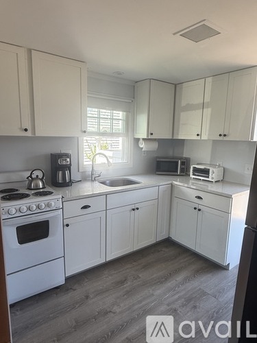 A kitchen with white cabinets and a stove top oven.