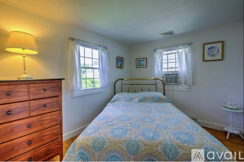 A bedroom with a bed, dresser, and window.