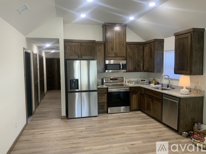 A kitchen with wooden cabinets and stainless steel appliances is available for rent.