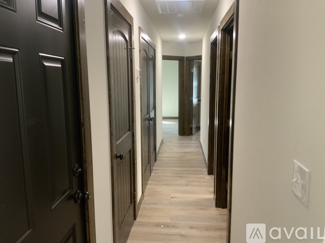 A long hallway with dark wood doors and light wood floors.