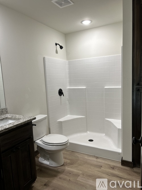 A white tiled shower with a toilet and sink in a bathroom.
