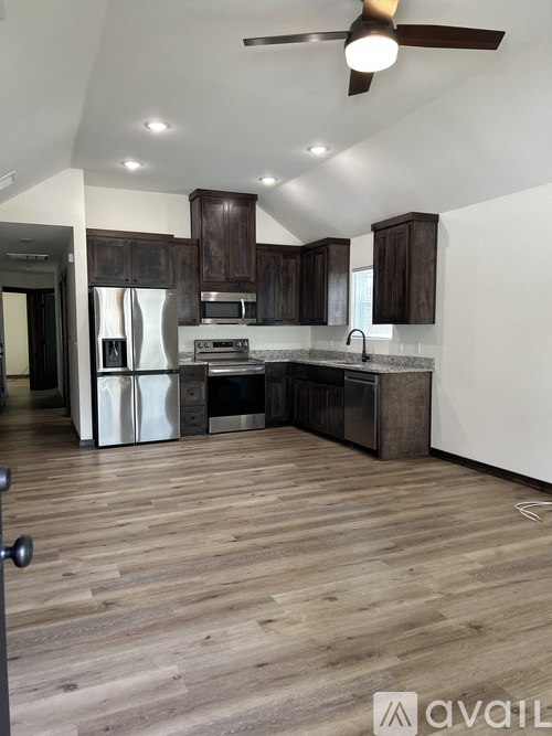 A kitchen with wooden floors and a ceiling fan.