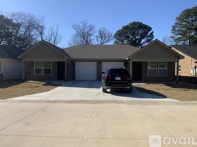 A black car is parked in front of a house with a garage.