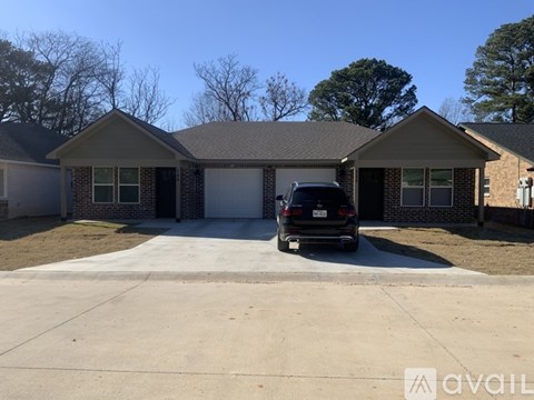A black car is parked in front of a house with a garage.