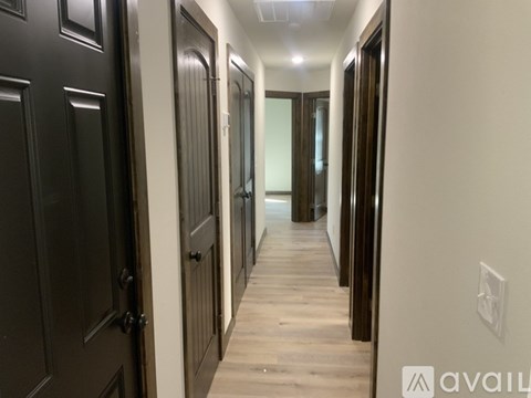 A long hallway with dark wood doors and light wood floors.