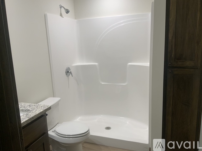 A white bathroom with a toilet, sink, and shower.