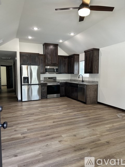 A kitchen with wooden floors and a ceiling fan.