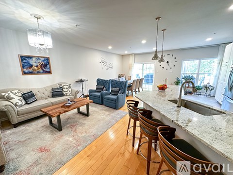 A living room with a couch, chairs, and a painting on the wall.