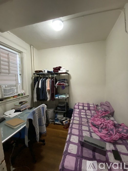 A bedroom with a bed, desk, and closet.