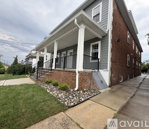 A brick house with a porch and a sign that says "AVAILABLE".