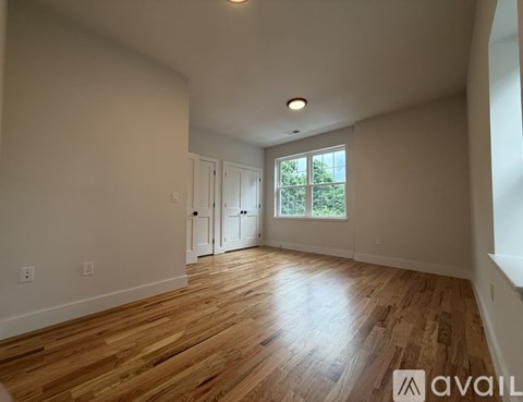 A room with wooden flooring and a window with a view of trees.