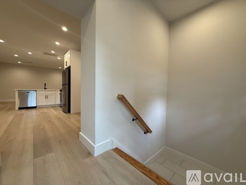 A spacious room with wooden flooring and a staircase with wooden steps and railings.