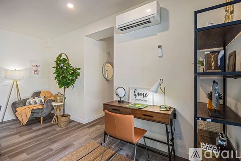 A room with a desk, chair, and a couch with a blanket on it.
