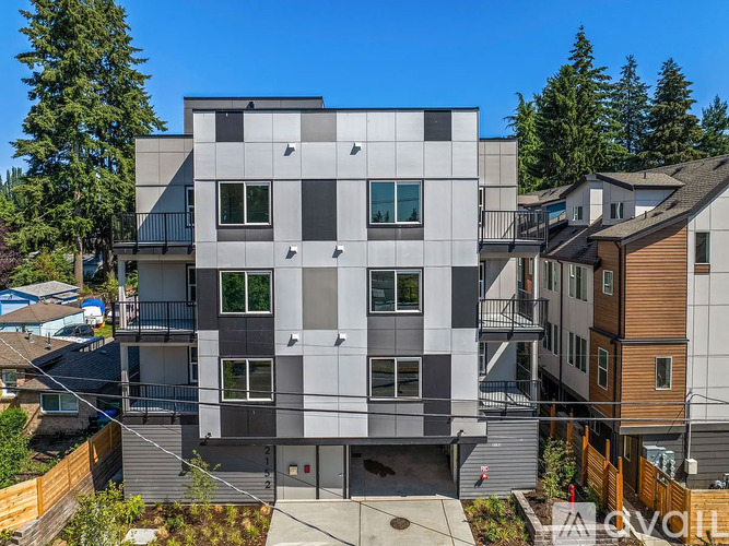 A modern multi-story building with a flat roof and a balcony on the second floor.