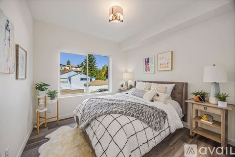 A bedroom with a large bed and a window showing a view of a house and trees.