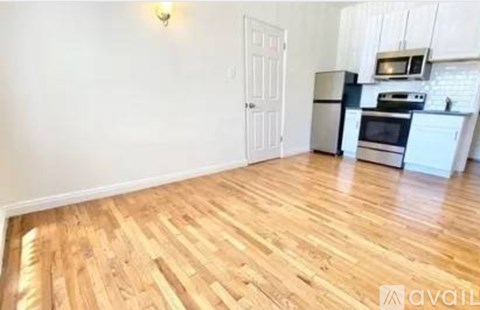 A kitchen with white cabinets and a wooden floor.