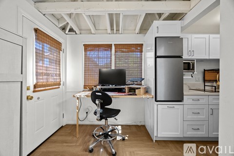 A kitchen with a desk and chair in the middle.