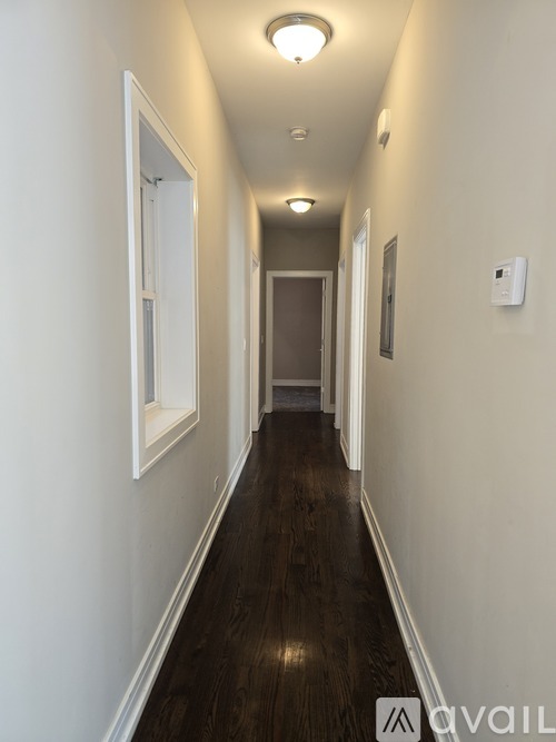 A long hallway with a light on the ceiling and a door at the end.