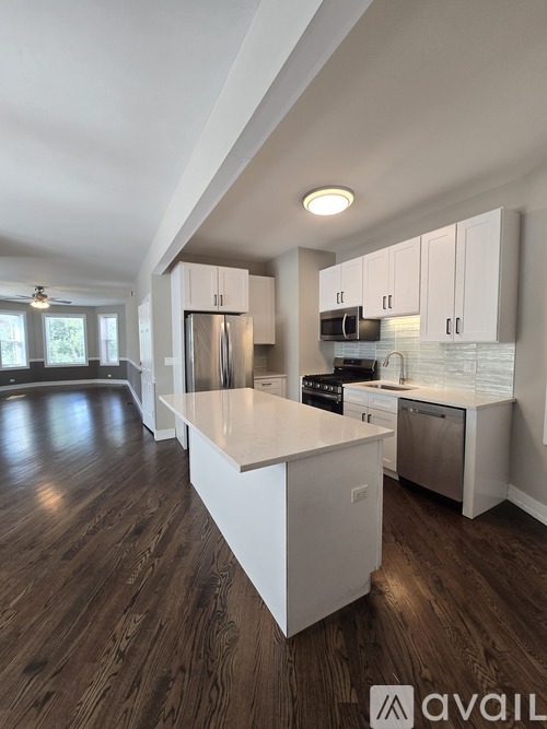 A modern kitchen with white cabinets and a wooden floor.