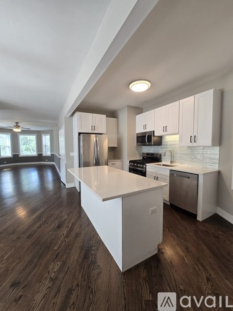 A modern kitchen with white cabinets and a wooden floor.