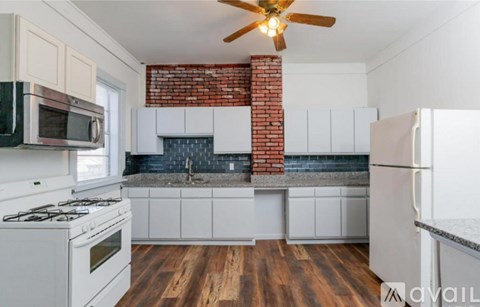 A kitchen with white cabinets and a brick chimney.