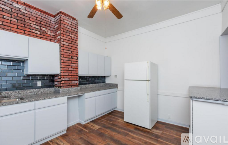 A kitchen with white cabinets and a brick accent wall.