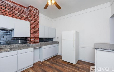 A kitchen with white cabinets and a brick accent wall.