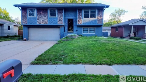 A blue house with a grey garage door and a red mailbox.