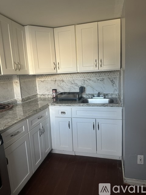A kitchen with white cabinets and a marble backsplash.