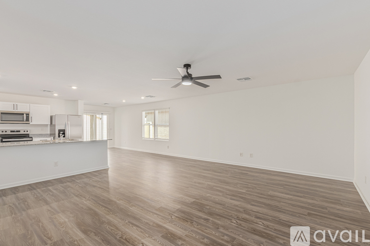 A spacious room with a ceiling fan and wooden flooring.